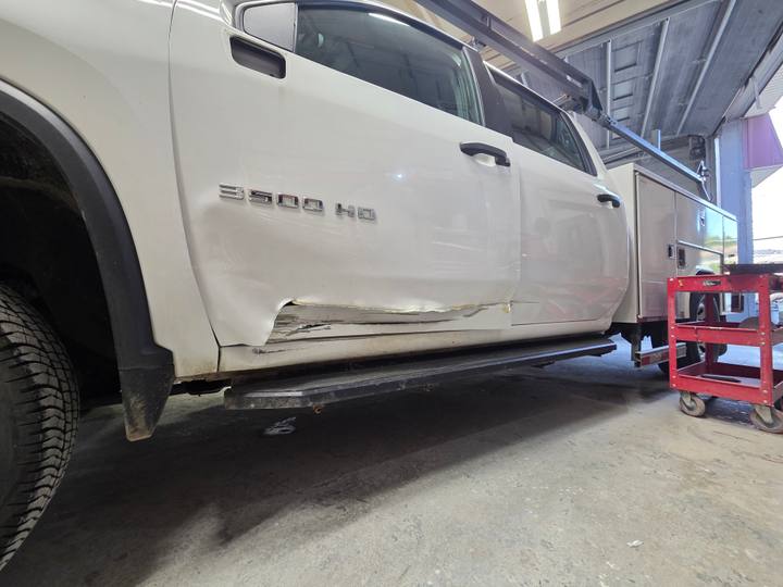 Before: driver's-side collision damage on a white Chevrolet 3500HD work truck