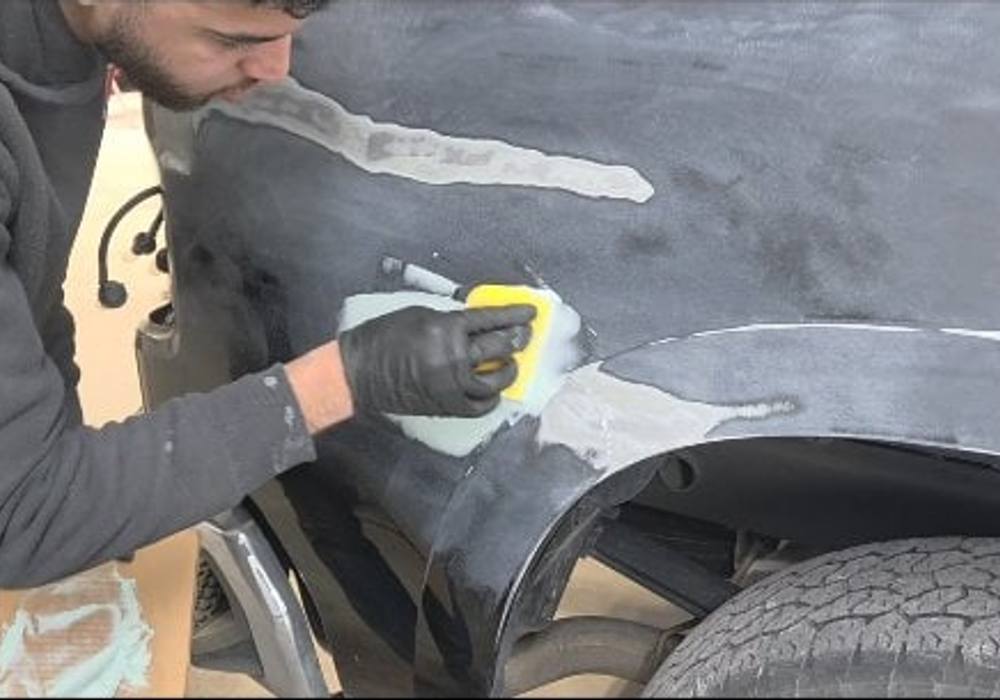 Technician sanding body filler on a vehicle fender at Mickey's Auto Body in Kearny, NJ