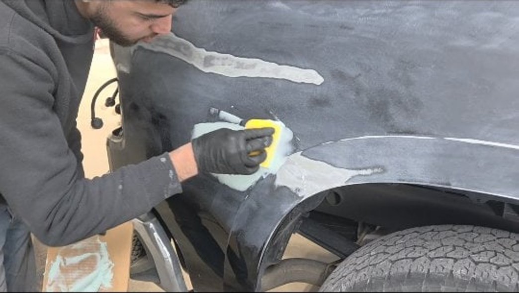 Technician sanding body filler on a vehicle fender at Mickey's Auto Body in Kearny, NJ
