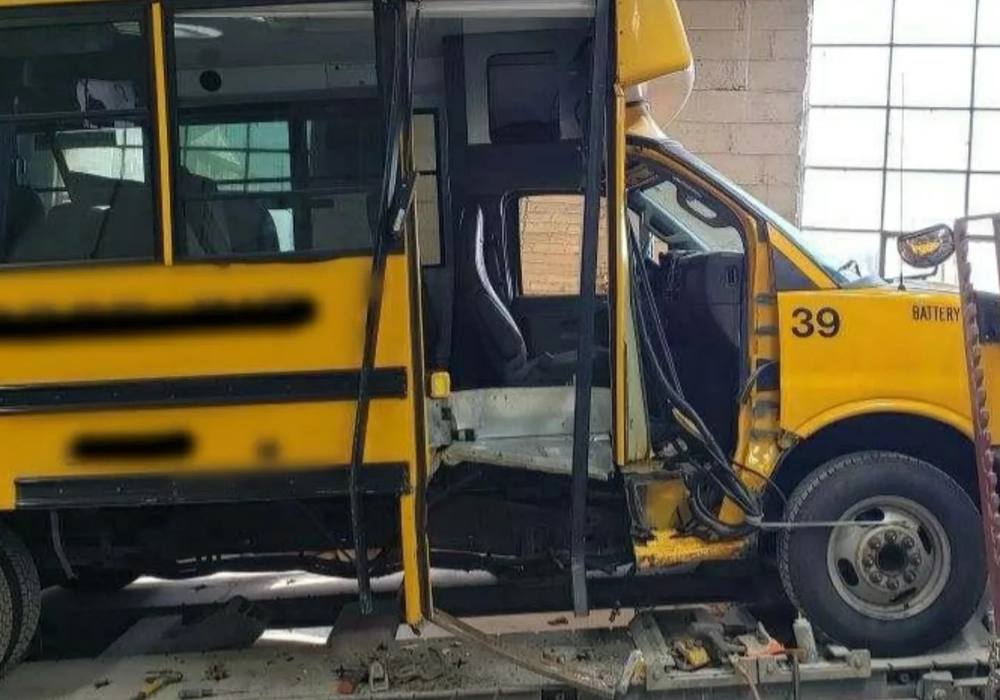 Yellow Collins school bus on the frame straightening rack at Mickey's Auto Body, the collision repair shop serving Newark, NJ