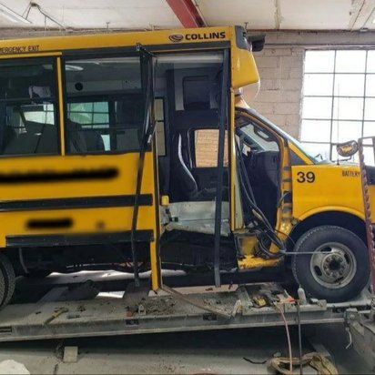 Yellow Collins school bus on the frame straightening rack at Mickey's Auto Body