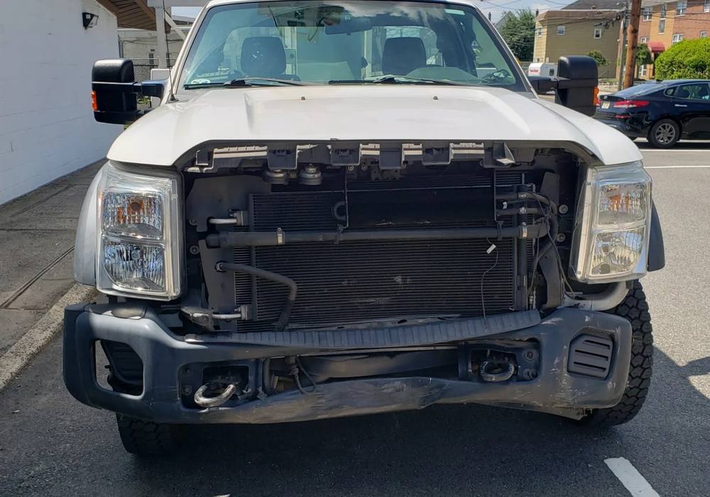 White utility truck with its front end stripped for collision repair at Mickey's Auto Body in Kearny, NJ