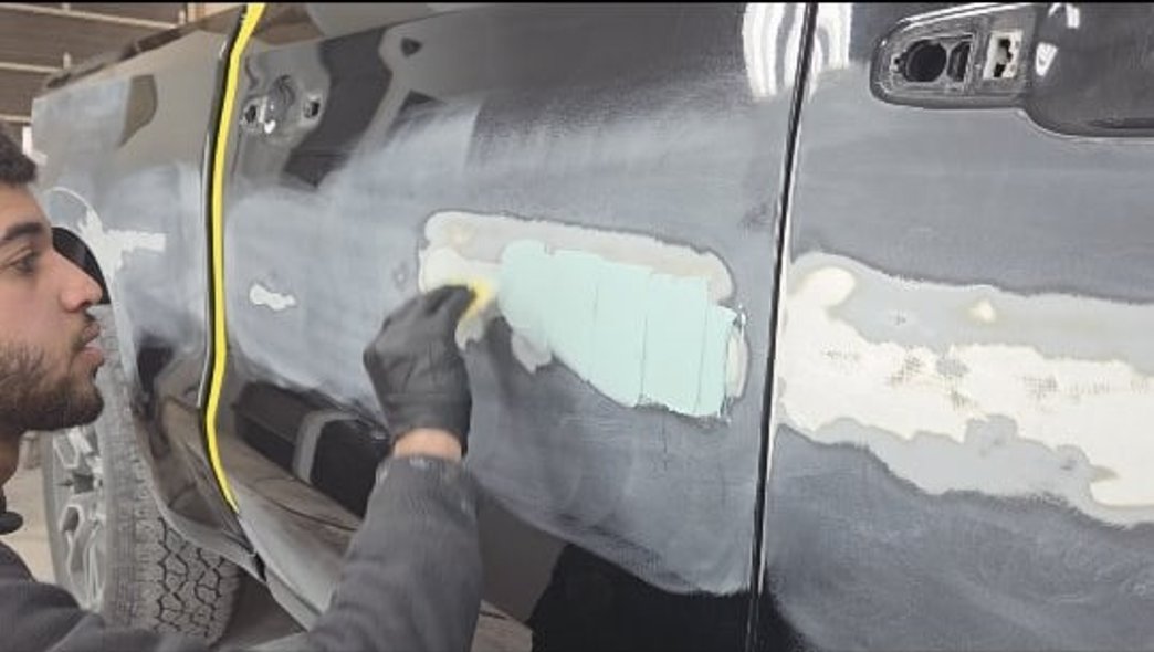 Technician applying body filler to a commercial truck door at Mickey's Auto Body in Kearny, NJ